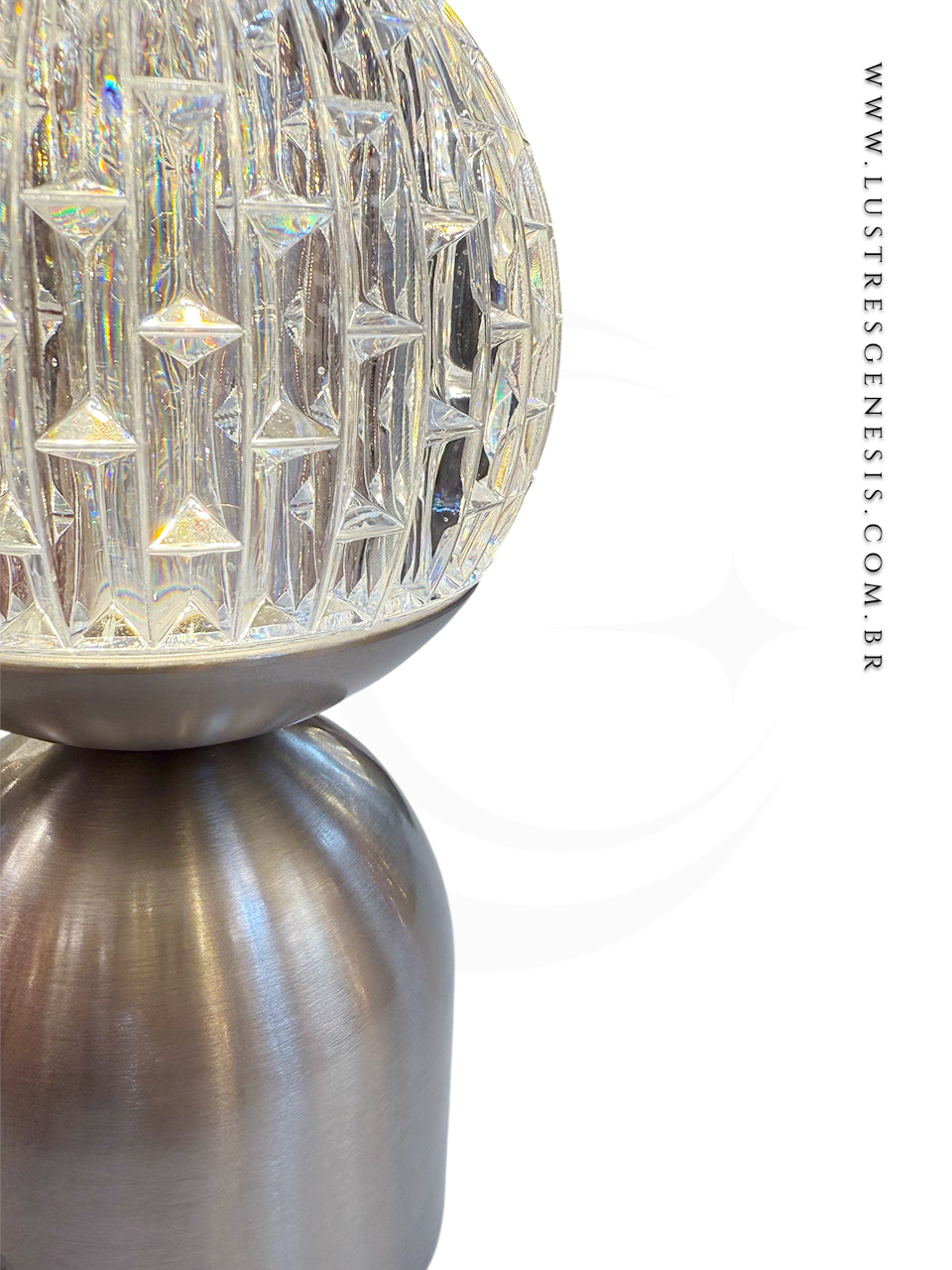 Luminária de bancada, design contemporâneo, com base em metal prata e globo de cristal transparente.
